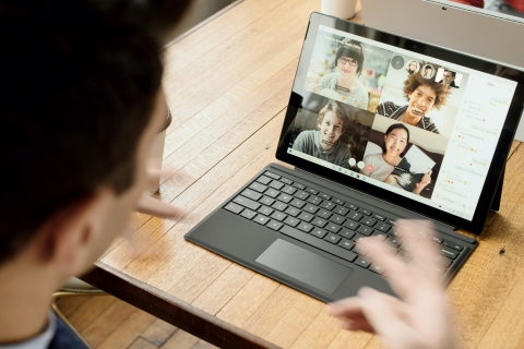 Person talking with hands while looking at a laptop screen with four coworkers' on video